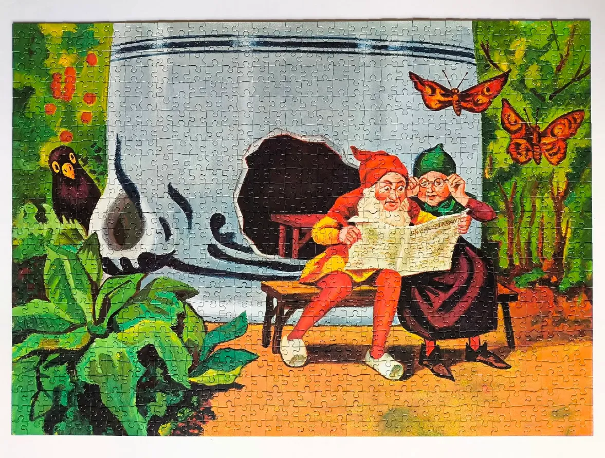Two elderly gnomes reading a newspaper on a bench in front of a giant ceramic pot