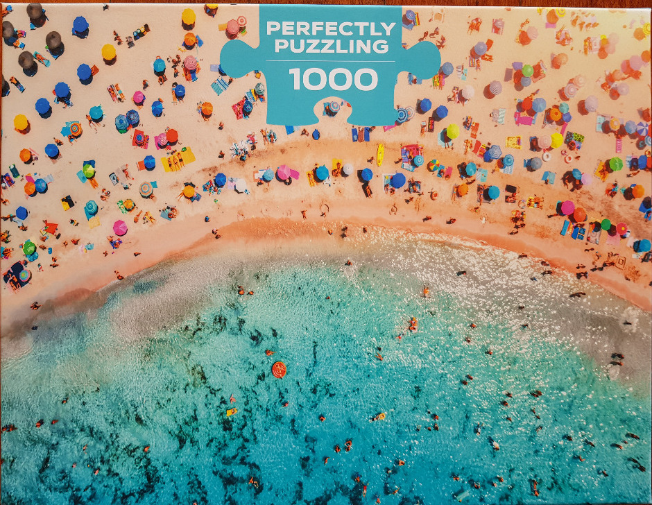 Aerial photograph of a crowded sandy beach with colorful umbrellas and clear turquoise ocean water.