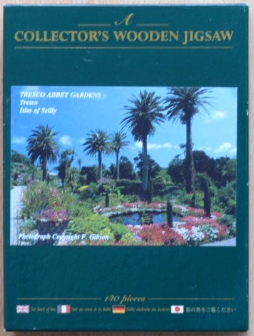 A sunny photograph of the sub-tropical Tresco Abbey Gardens on the Isles of Scilly featuring tall palm trees and a pond.