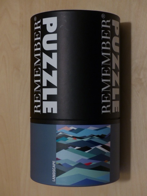 A cylindrical container featuring a stylized, abstract mountain landscape in shades of blue, teal, and grey.