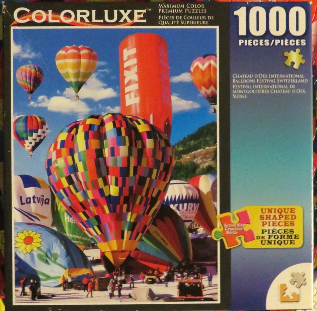 Multiple colorful hot air balloons floating over a snowy mountain landscape.