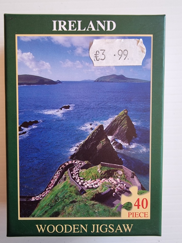 A flock of sheep walking along a cliffside path overlooking the ocean in Ireland.