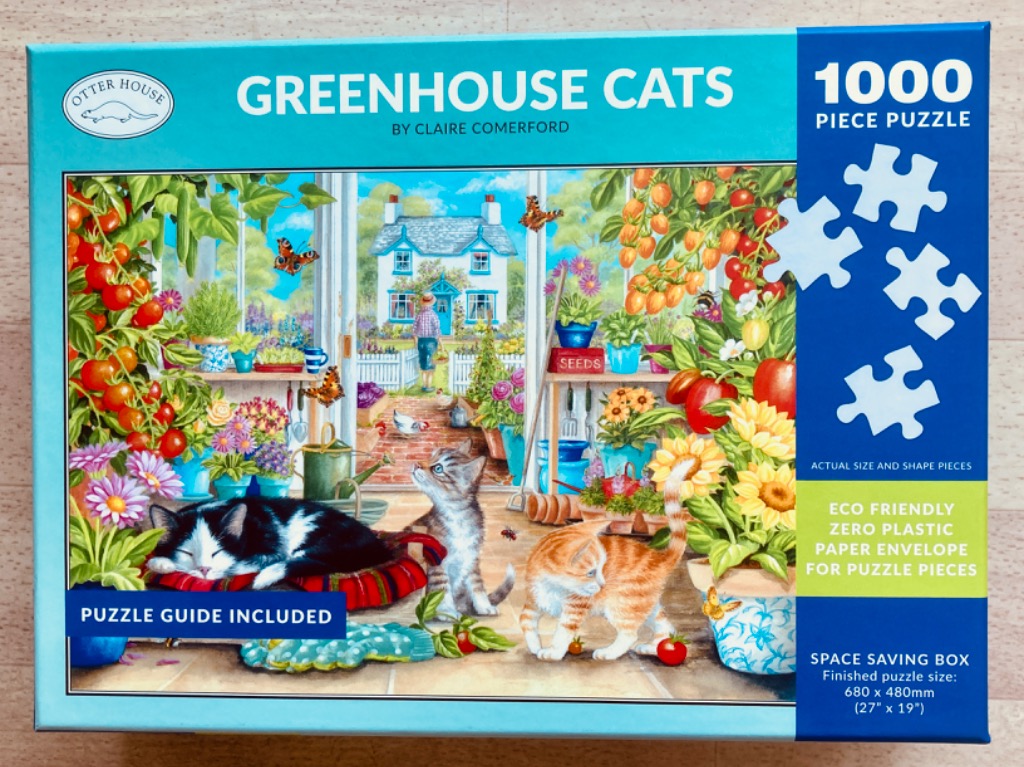 Three cats lounging in a vibrant greenhouse filled with vegetables, flowers, and garden tools.