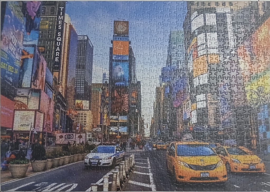 A view of Times Square in New York City with iconic yellow taxis and advertising billboards under a clear sky.