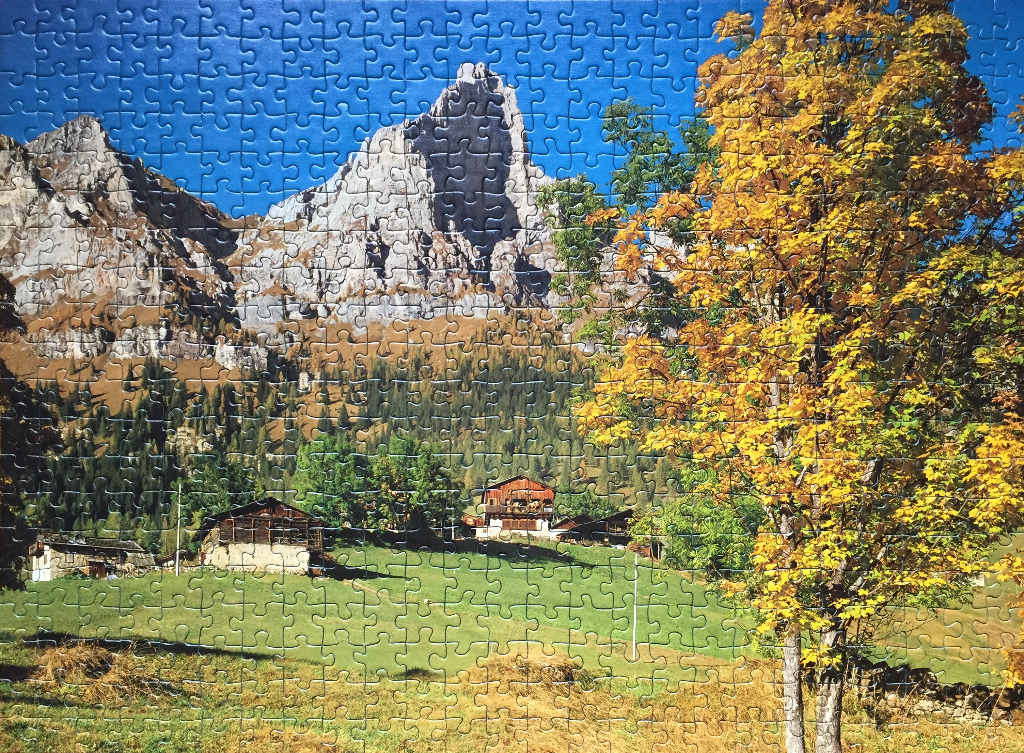 A scenic mountain landscape with autumn trees, a wooden chalet, and a vibrant blue sky.