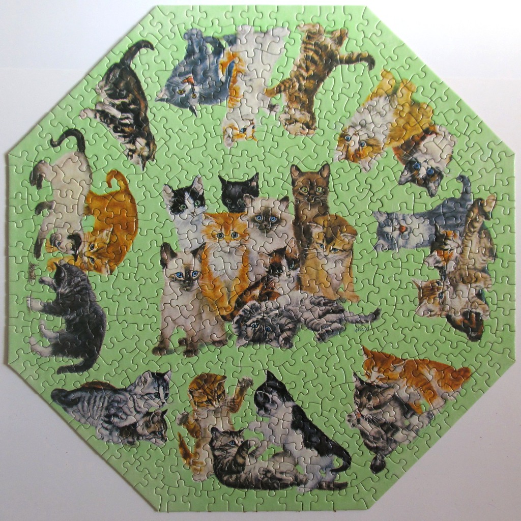 A circular collage of many different breeds and colours of kittens on a solid pale green background.