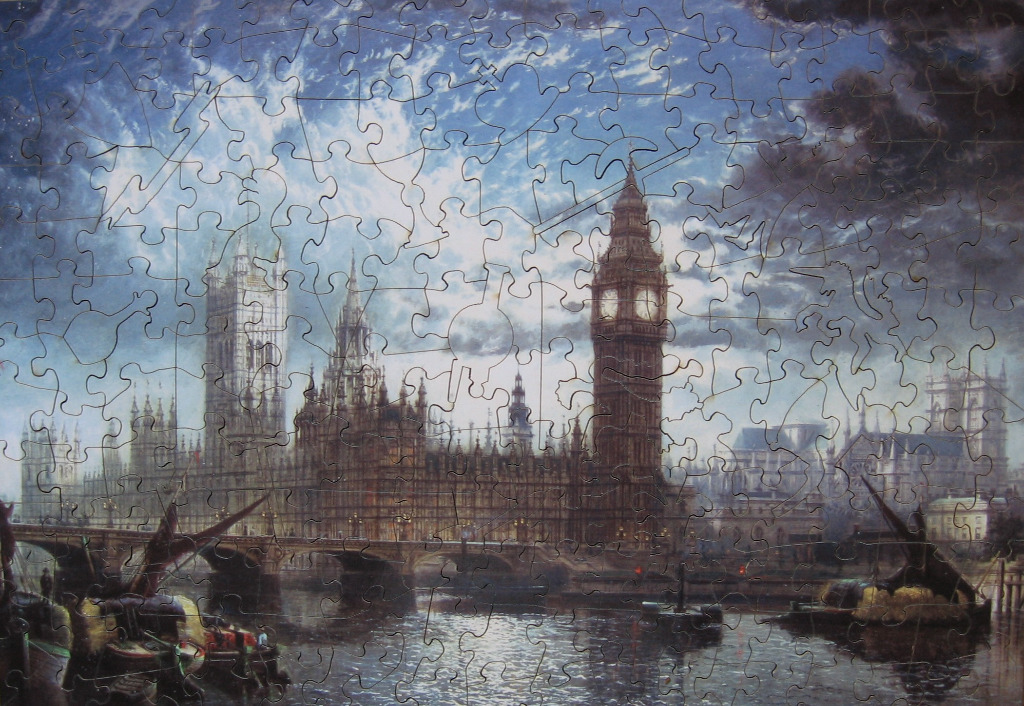 The Palace of Westminster and Big Ben under a dramatic, moody sky at twilight by a river.