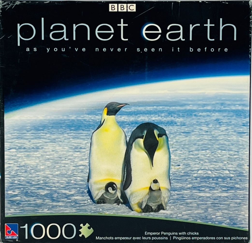 Two emperor penguins standing on ice, each protecting a chick between their feet, against a backdrop of Earth from space.