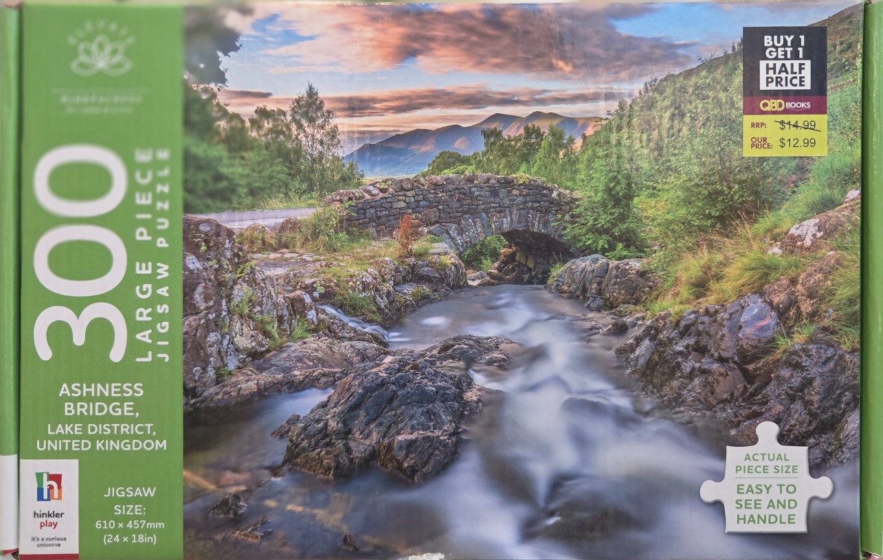 A scenic photograph of Ashness Bridge in the Lake District, featuring a stone bridge over a flowing mountain stream.