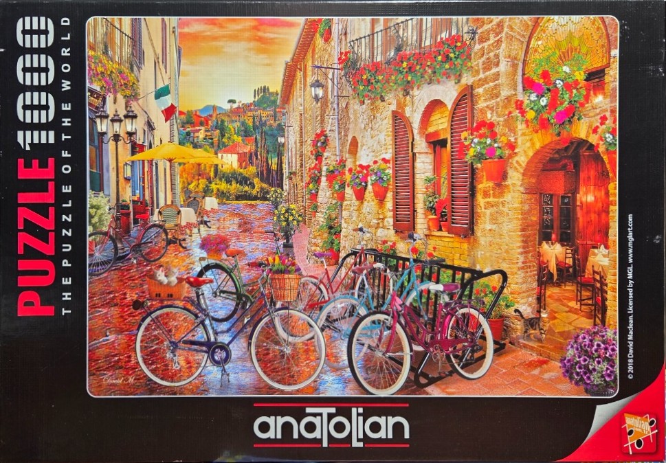 A European street scene with bicycles parked along a stone building adorned with flowers under a sunset sky.