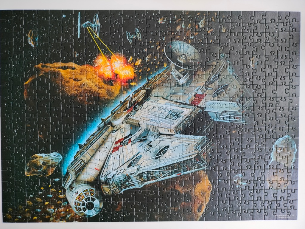 The Millennium Falcon starship maneuvering through an asteroid field while being pursued by TIE fighters.