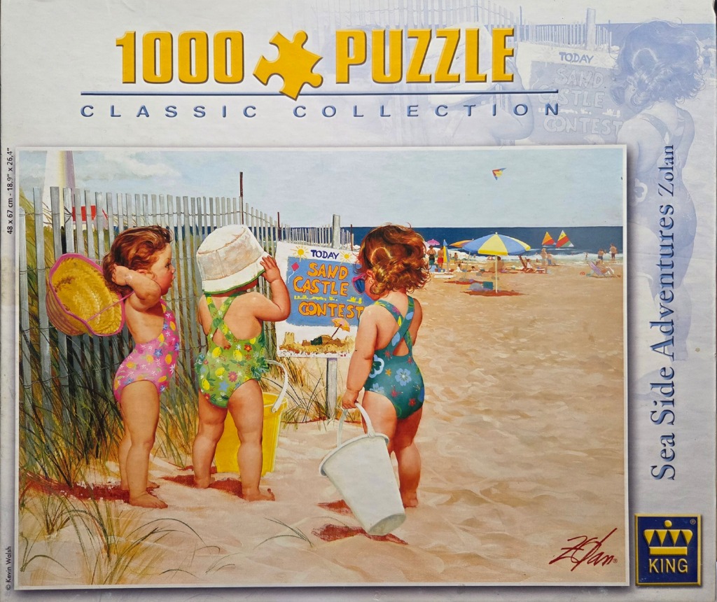 Three toddlers in swimsuits look at a sandcastle contest sign on a sunny beach.