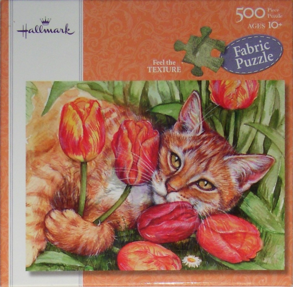 An orange tabby cat resting in a garden of red and orange tulips.