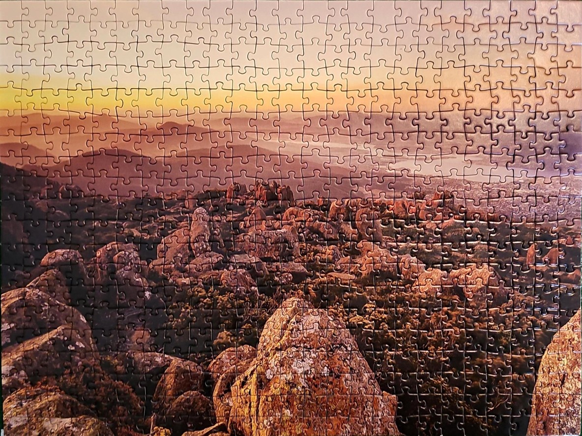 Panoramic view of a rocky landscape at sunset with distant hills and a valley