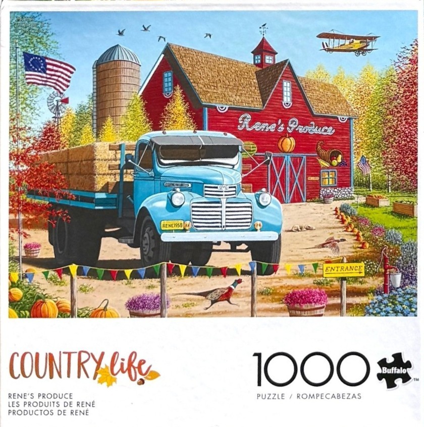 A vintage blue truck loaded with hay sits in front of a red barn in an autumn landscape.
