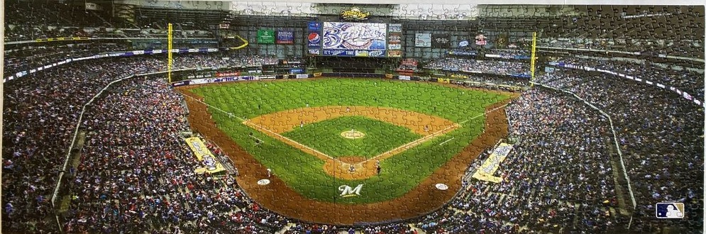 Panoramic view of an indoor baseball stadium packed with fans on a green field.