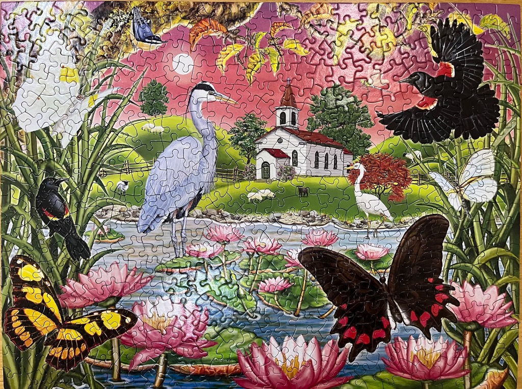 A vibrant pond scene featuring a great blue heron, red-winged blackbirds, butterflies, and a small chapel.