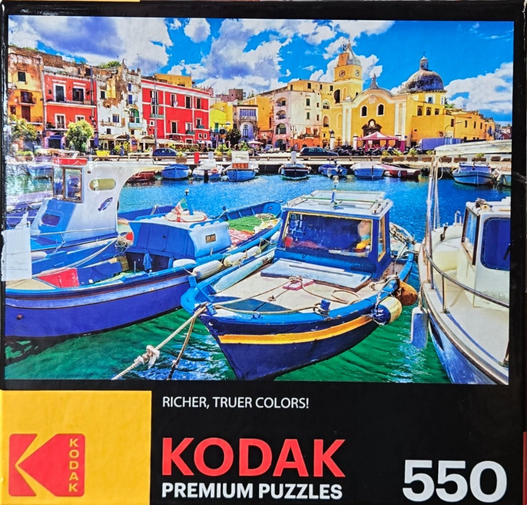 Brightly colored fishing boats moored in a Mediterranean harbor with a backdrop of colorful Italian buildings.