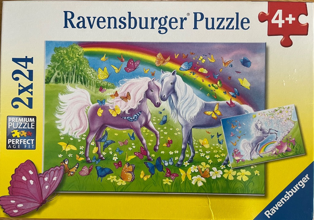 Two horses standing in a lush green meadow with a rainbow and many colorful butterflies.