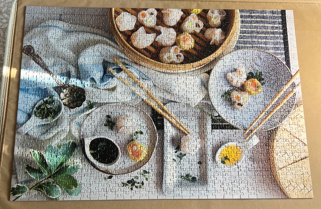 A top-down view of a dim sum meal with steamer baskets, plates of dumplings, dipping sauces, and chopsticks.