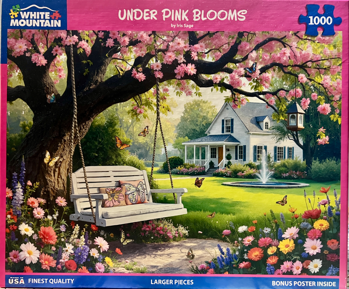A white wooden porch swing hanging from a large cherry blossom tree in a sunny, flower-filled garden.