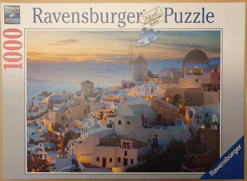 A scenic sunset view of the white-washed buildings and windmills of Oia, Santorini, Greece.