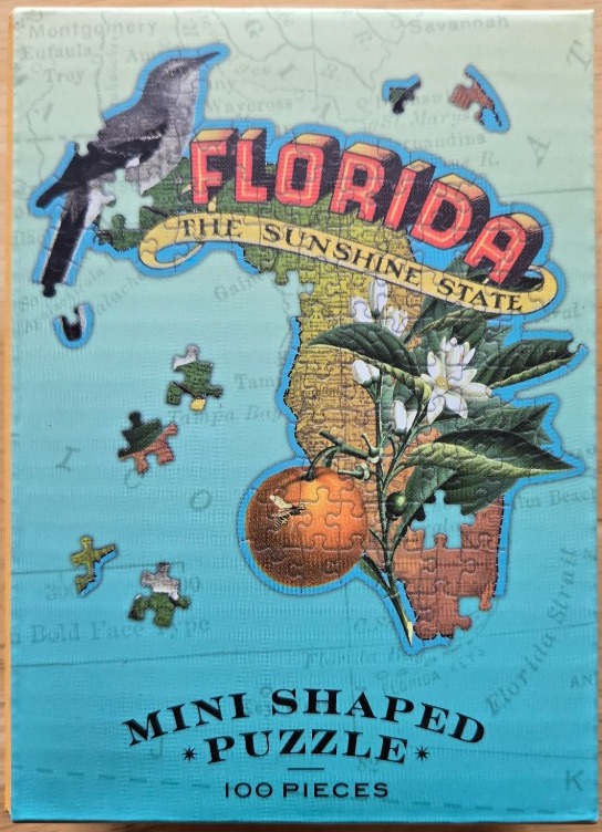 A vintage-style illustration of the Florida state map featuring a mockingbird, orange blossoms, and an orange.