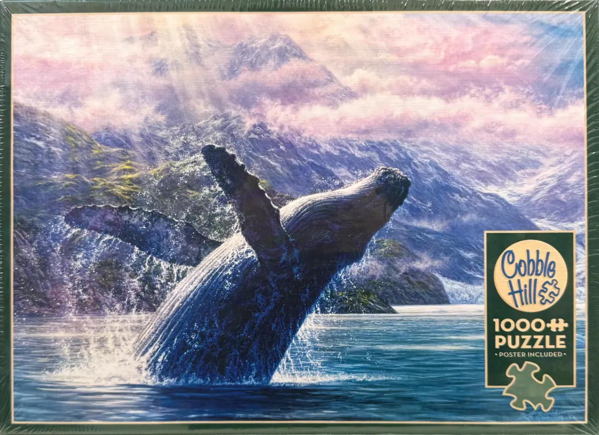 A humpback whale breaching out of the water against a dramatic mountain backdrop with soft pink and blue lighting.