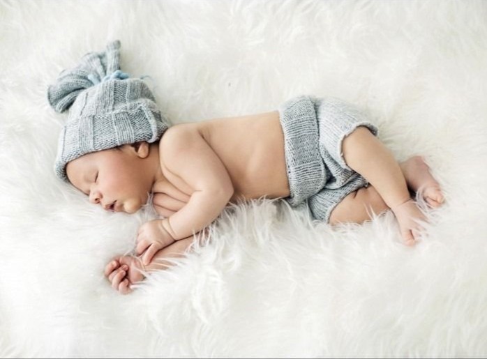 Newborn baby sleeping on a white faux fur rug