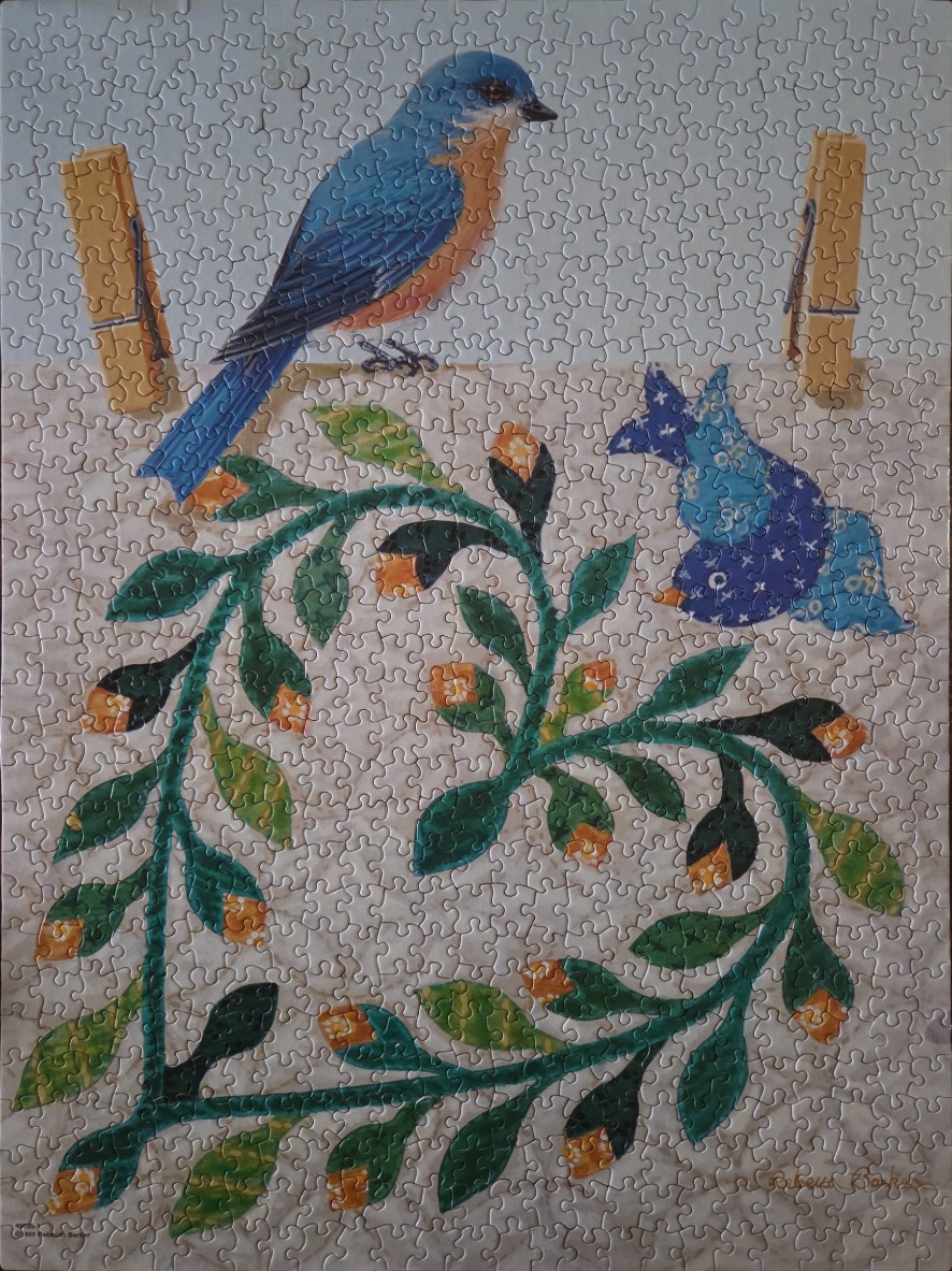 A bluebird perched on a line above a quilt pattern of green vines and flowers.