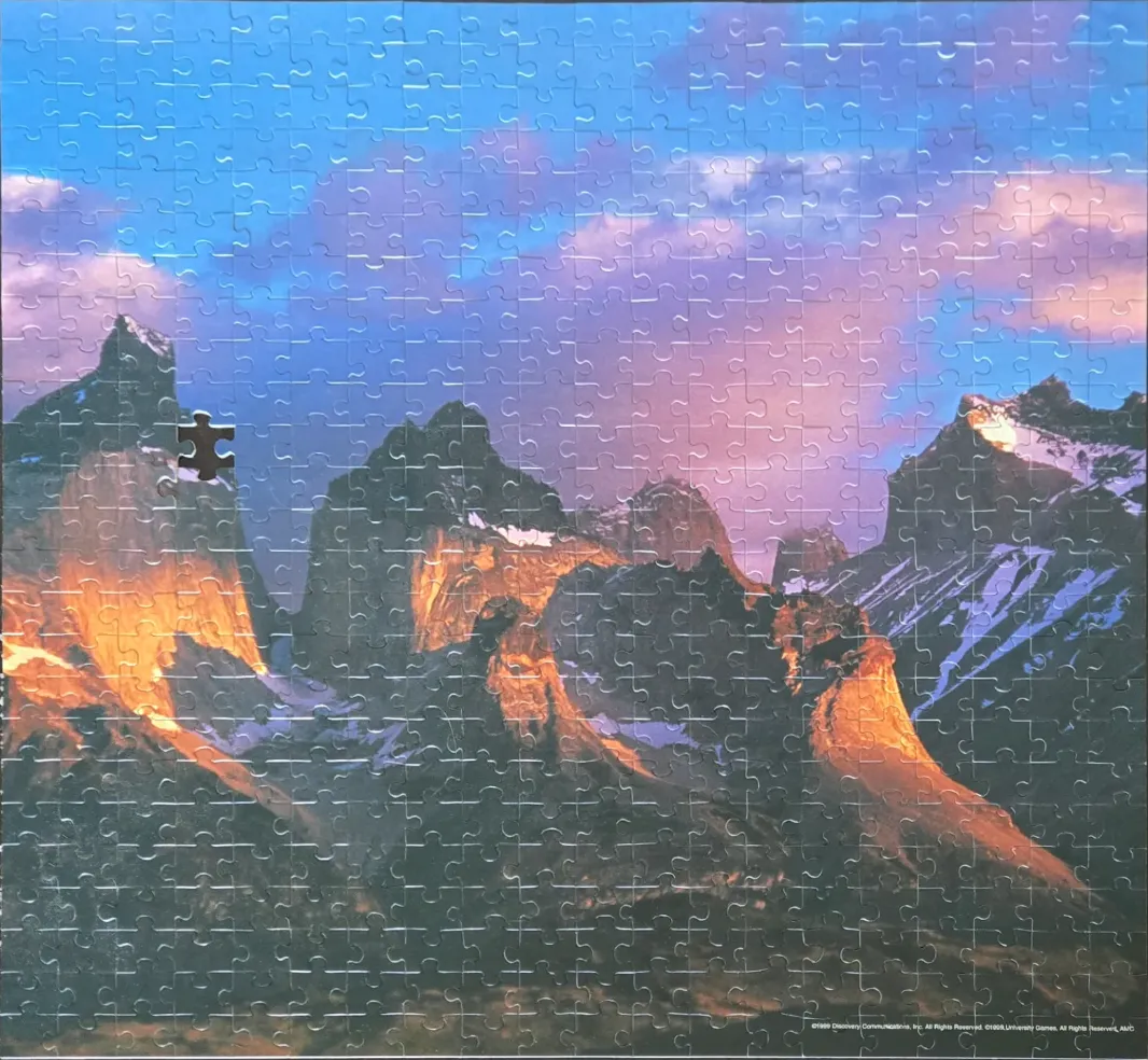 Majestic mountain peaks illuminated by sunset light against a vibrant purple and blue sky.