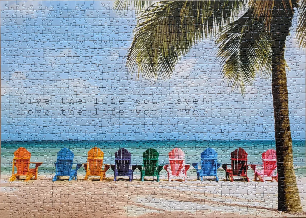 A row of nine colourful Adirondack chairs on a sandy beach under a palm tree with the inspirational text overlay.