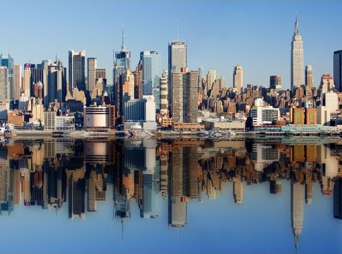 Panoramic view of the Midtown Manhattan skyline reflecting perfectly in calm water