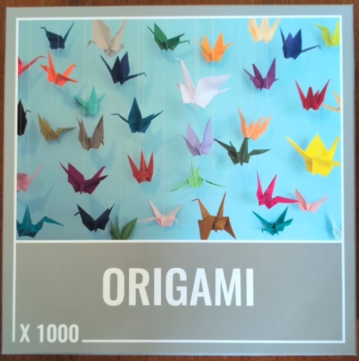 A collection of colorful origami paper cranes suspended against a bright light blue background.