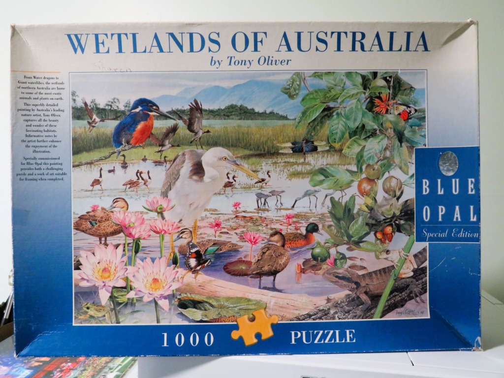 A detailed watercolor illustration of Australian wetlands featuring a blue kingfisher, a tall heron, ducks, and flora.