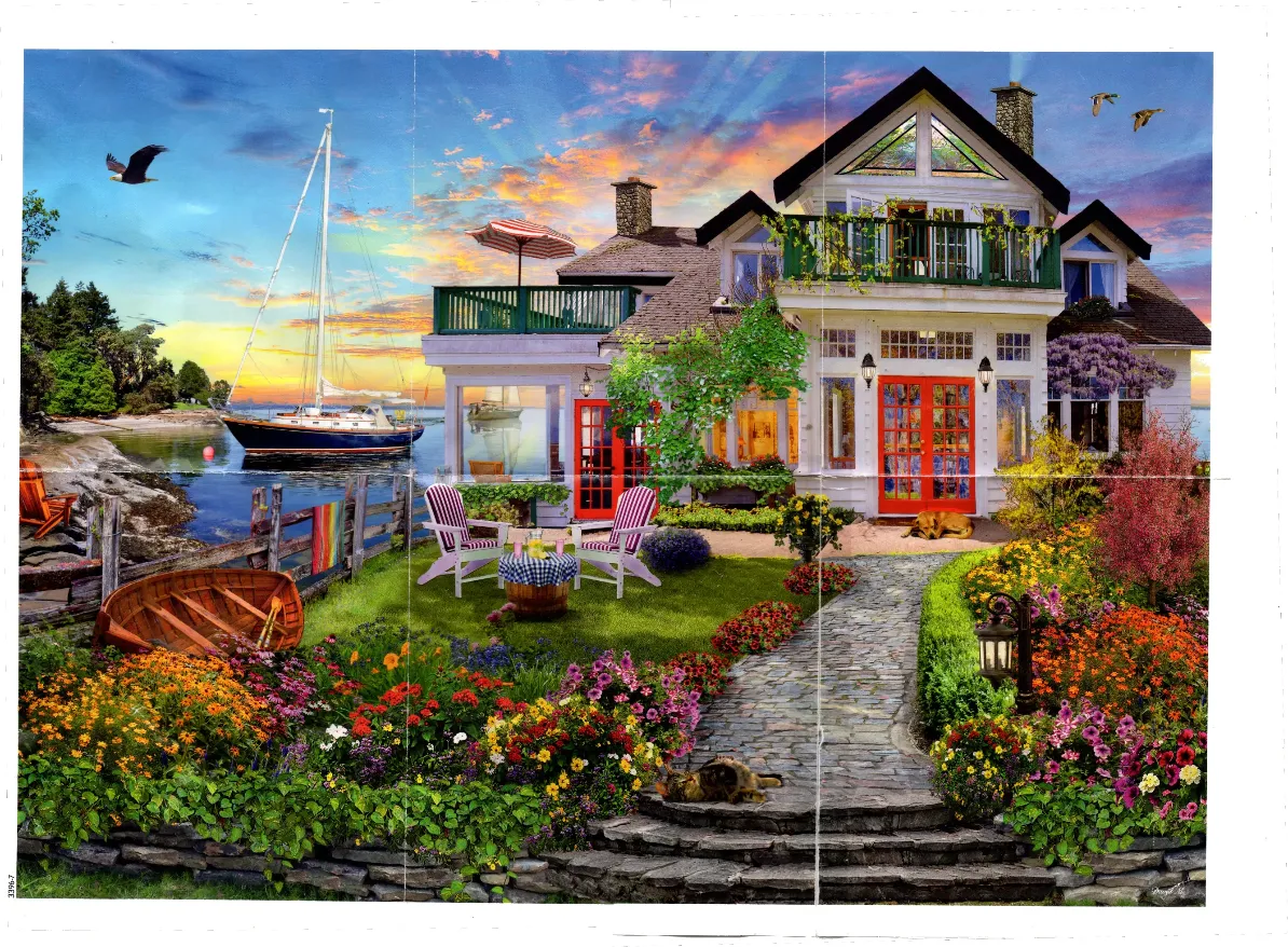 A cozy white lakeside cottage with a vibrant flower garden at sunset.