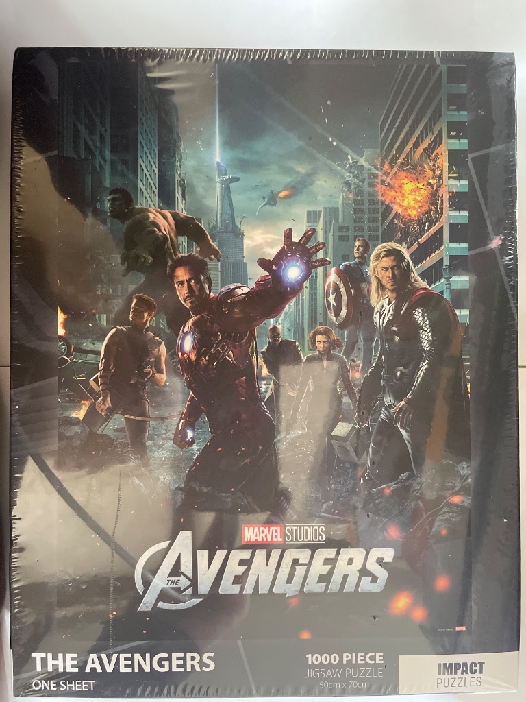 The Avengers superheroes standing together in a battle-worn city scene.
