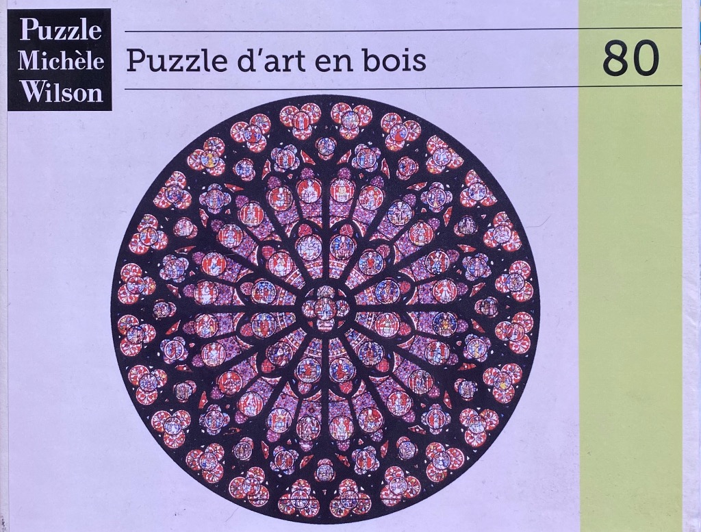 A circular, radial stained glass rose window design with intricate purple, red, and blue floral-like patterns.