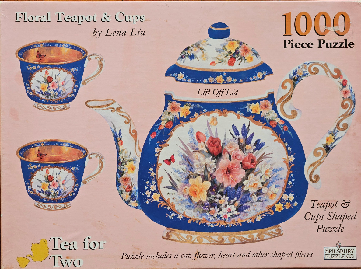 A floral-themed teapot and two matching teacups against a soft pink background.