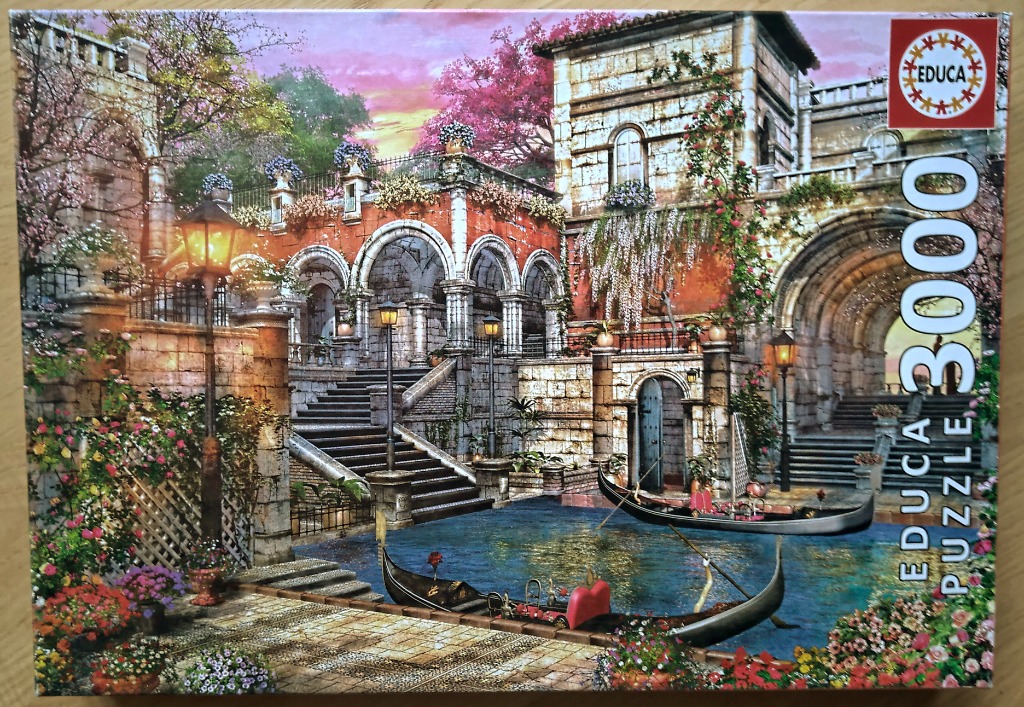 Venetian-style canal scene with stone architecture, bridges, and two gondolas at sunset.