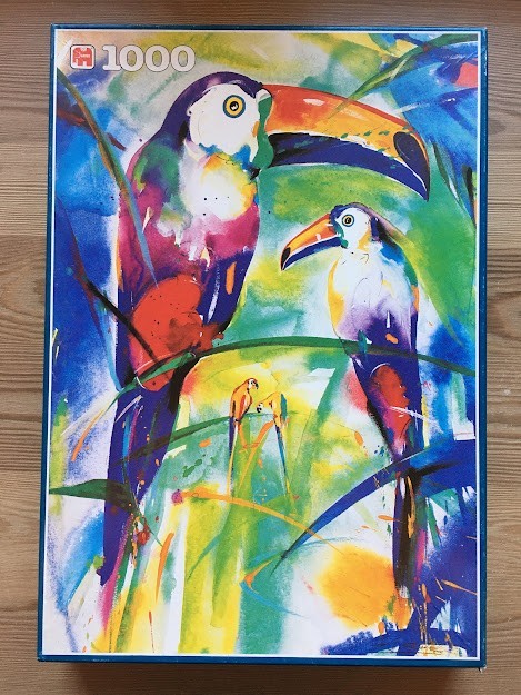 Watercolor painting of two large toucans perched amongst lush, colorful tropical foliage.