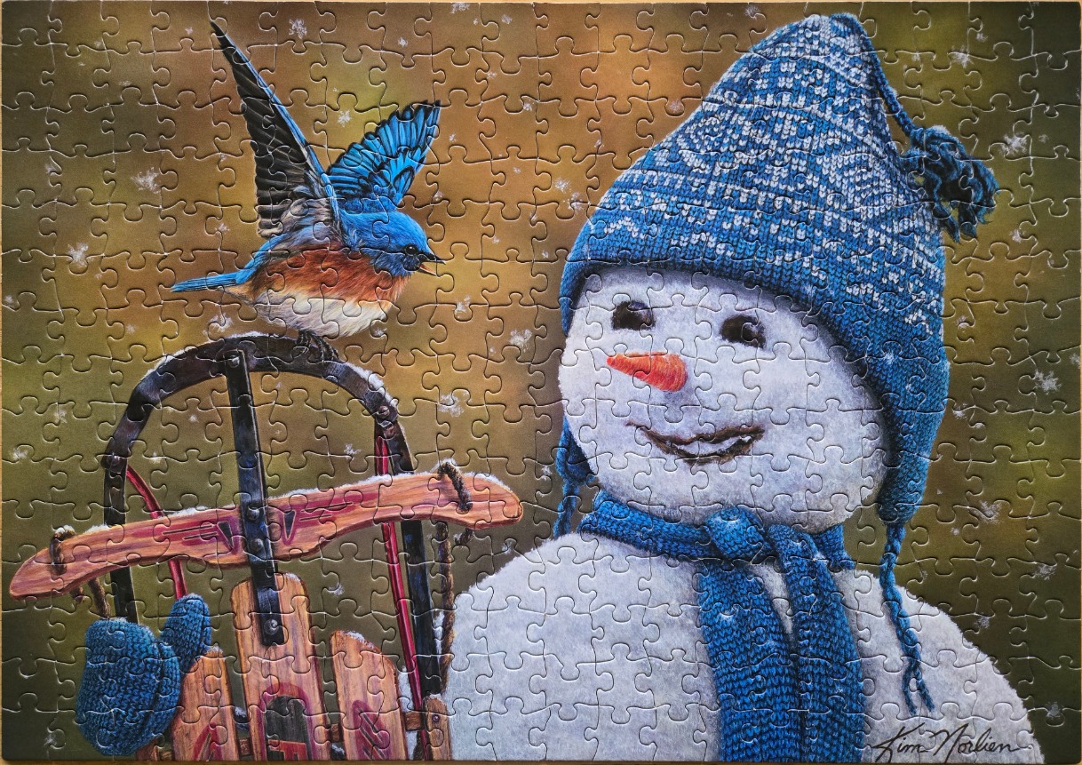A bluebird landing on a vintage wooden sled next to a smiling snowman wearing a blue knit hat and scarf.