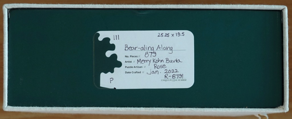 A rectangular box with a dark green cover and a white information label featuring handwritten text.