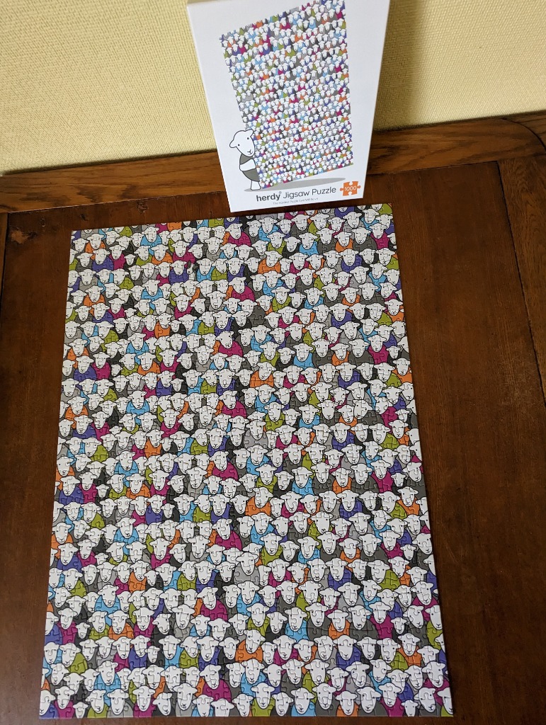A pattern of stylized cartoon sheep in various colors, including white, grey, blue, green, and pink.