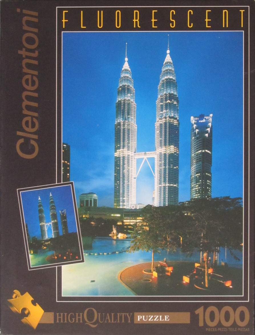 The Petronas Towers in Kuala Lumpur illuminated at twilight over a park and pool.