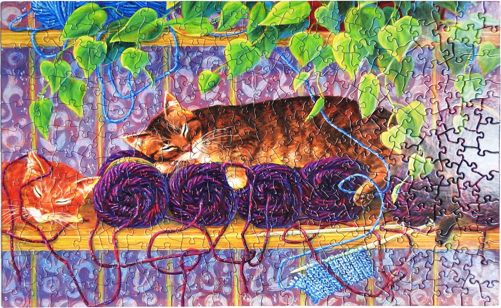 Two cats sleeping on a wooden shelf amongst balls of purple yarn and trailing green plants.