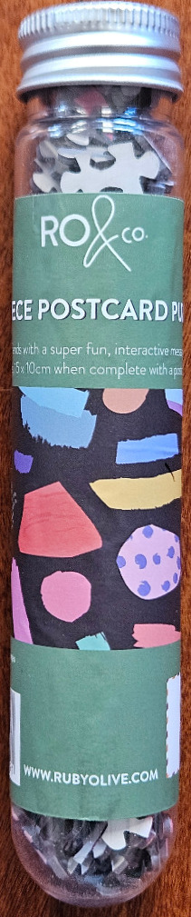 Clear tube with a label featuring an abstract pattern of colorful geometric shapes against a black background.