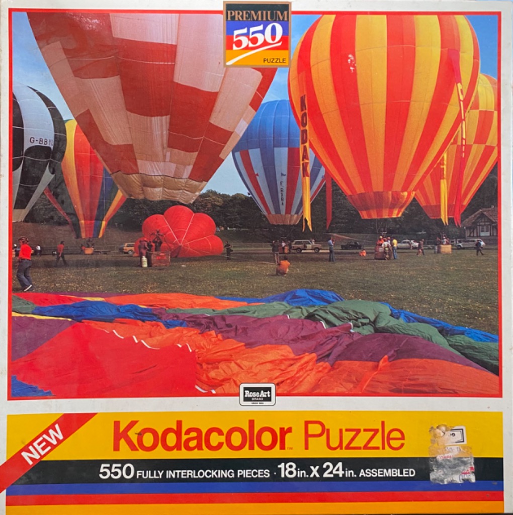A field of colorful hot air balloons in various stages of inflation under a blue sky.
