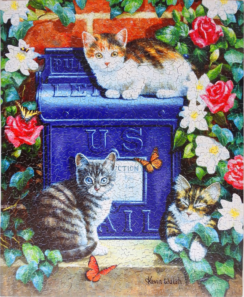Three kittens sitting on and around a blue US mailbox surrounded by roses and butterflies