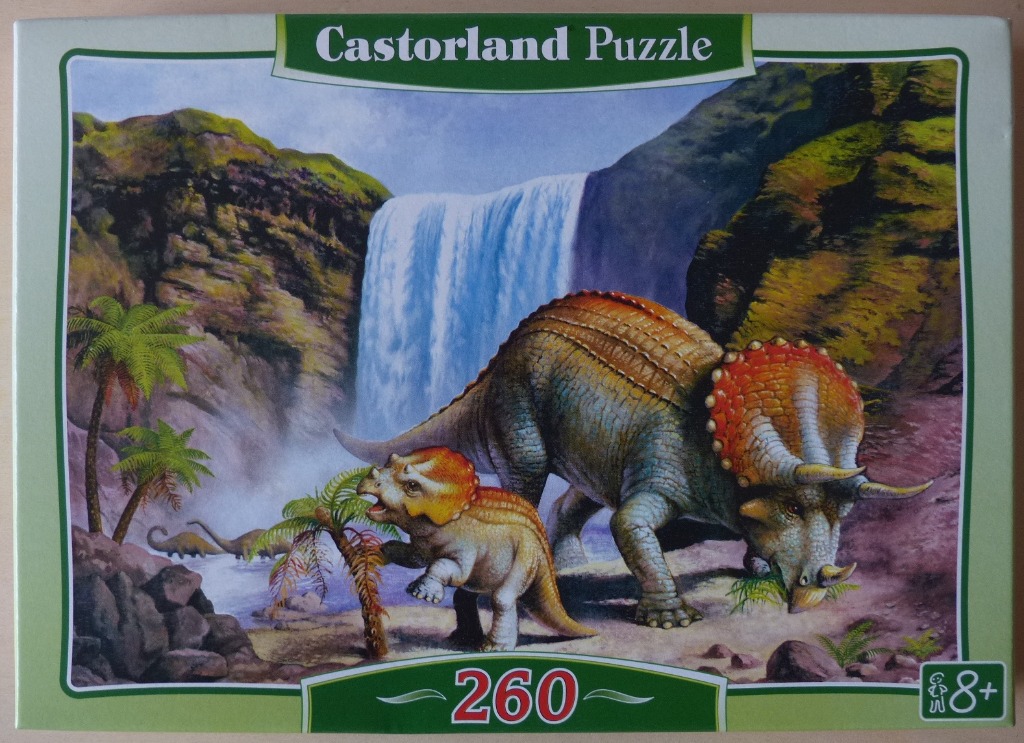 A mother triceratops and her young calf standing in front of a large waterfall in a prehistoric landscape.